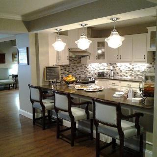 A modern kitchen featuring a stylish island with bar stools, elegant pendant lighting, and a patterned tile backsplash.