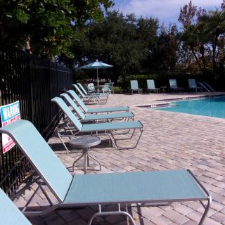 A serene outdoor pool area with sun loungers and an umbrella, perfect for relaxation.