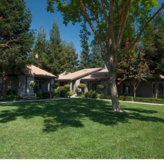 A single-story house surrounded by trees and a well-maintained lawn.