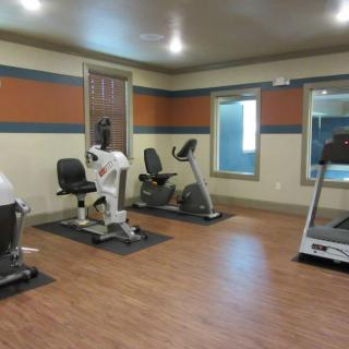 A small gym room featuring exercise equipment including a treadmill and stationary bikes.