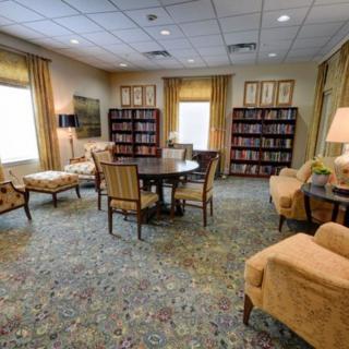 A cozy reading room with bookshelves, comfortable chairs, and a central table.