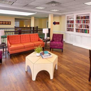 A cozy living room with vibrant furniture and a built-in bookshelf.