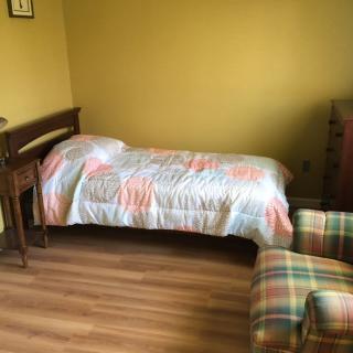 A cozy bedroom with a single bed and a plaid armchair.