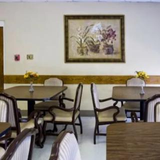 A well-arranged dining area with tables, chairs, and a floral painting on the wall.