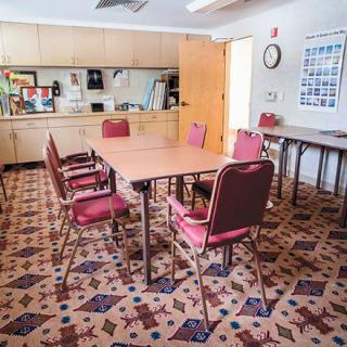 A small meeting room with a table, chairs, and a kitchen area.