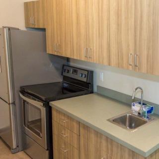 A modern kitchen with stainless steel appliances, featuring a refrigerator, oven, and a small sink.