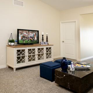 A cozy living room featuring a television, elegant furniture, and a neutral color palette.