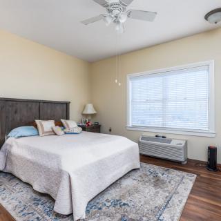 A cozy bedroom with a large bed, soft lighting, and a window allowing natural light.
