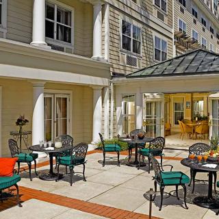 A sunny patio area with tables and chairs outside a building.