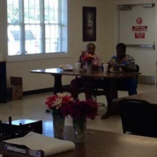 Two people sitting at a table in a well-lit room with flowers.