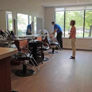 A person setting up a salon chair while another observes in a bright, modern salon.