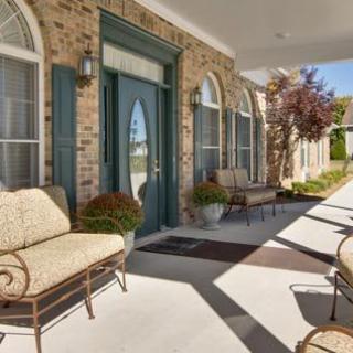 A charming porch with comfortable seating, brick walls, and arched windows.