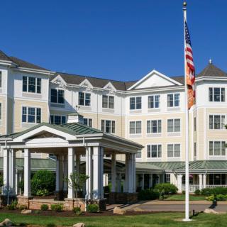 A four-story hotel building with a prominent American flag in front.