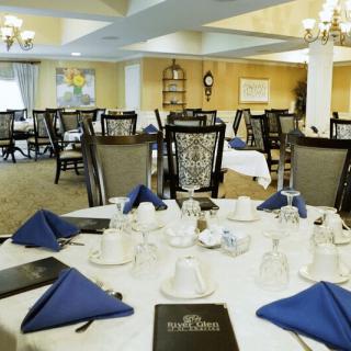 Elegant dining room with tables set for service, featuring blue napkins and stylish chairs.