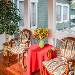 A cozy sitting area with two elegant chairs and a table adorned with a vase of flowers, set by large windows.