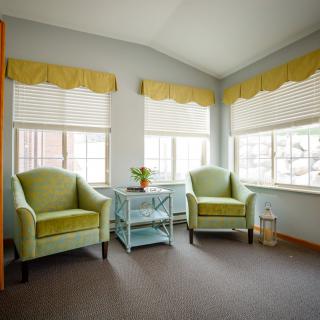A cozy living room corner with two green chairs and large windows letting in natural light.