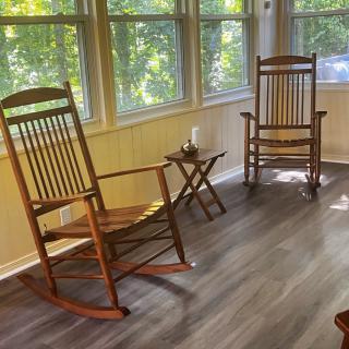 A cozy sunroom with two wooden rocking chairs and a small table, basking in natural light.