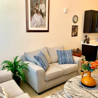 A cozy living room featuring a comfortable sofa, decorative artwork, and vibrant plants.