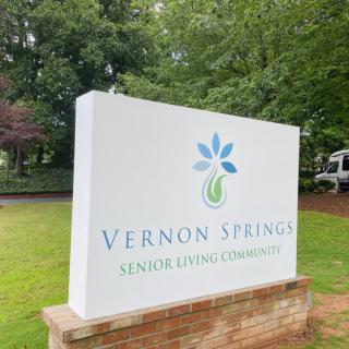 Sign for Vernon Springs Senior Living Community surrounded by greenery.