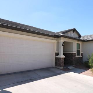 A modern single-family home with a spacious garage and clear blue skies overhead.
