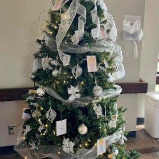 A beautifully decorated Christmas tree adorned with white ribbons and ornaments, bringing festive cheer to the space.