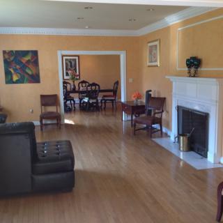 A spacious living area with an adjoining dining room, featuring hardwood floors and a fireplace.