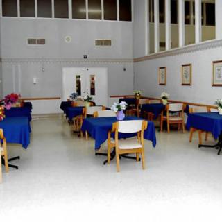 An indoor dining area with several tables covered in blue tablecloths and surrounded by chairs.