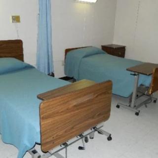 A hospital room with two neatly made patient beds and minimal furnishings.