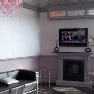 A modern living room with a sleek sofa, mounted television, and stylish fireplace.