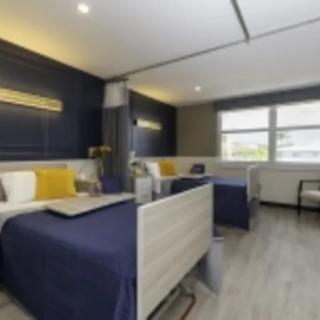 A modern hospital room with two patient beds, featuring a stylish interior and comfortable amenities.