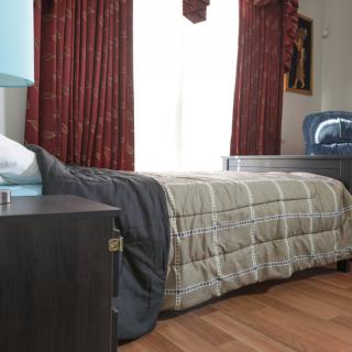 A cozy bedroom with a single bed and wooden furnishings.