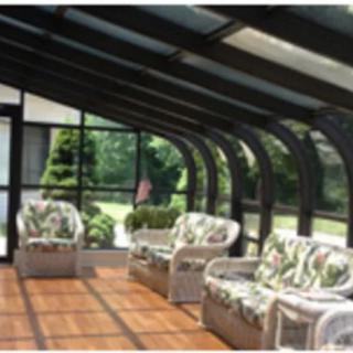 A cozy sunroom with wicker furniture and a glass-enclosed design.