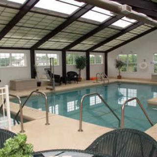 A serene indoor swimming pool area with a glass roof and seating.