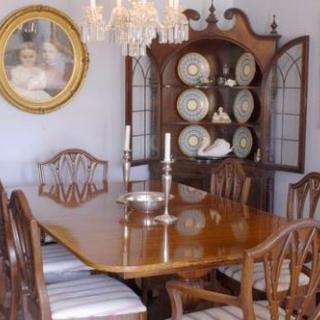 A traditional dining room featuring a wooden table with matching chairs, a chandelier overhead, and a china cabinet displaying dishware.
