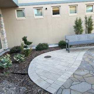 A serene outdoor space featuring a stone pathway, garden plants, and a bench for relaxation.