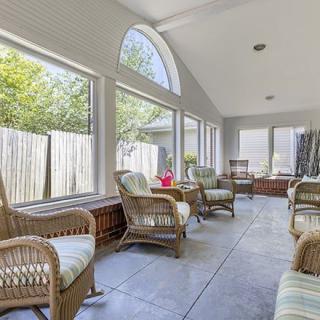 A bright sunroom featuring wicker furniture and large windows allowing an abundance of natural light.