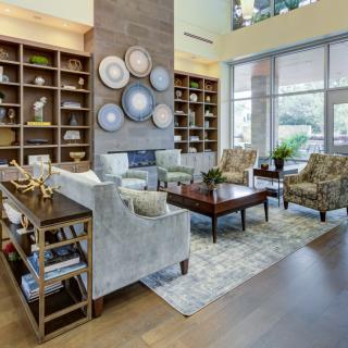 A cozy living room with elegant furniture and decorative elements, illuminated by natural light from large windows.