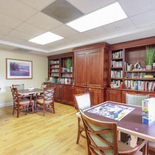 A cozy office space with wooden furniture and a well-stocked bookshelf, perfect for studying or meetings.