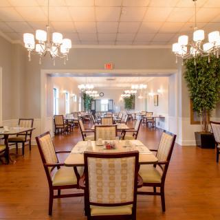 Elegant dining area with neatly arranged tables and chairs, illuminated by decorative chandeliers.