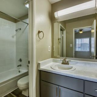 A modern bathroom featuring a shower, toilet, and sink with neutral-toned walls.