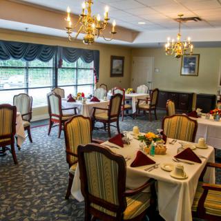 An elegant dining room with neatly arranged tables and chairs, adorned with chandeliers.
