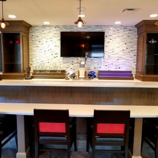 A stylish home bar with modern seating and a wall-mounted television.