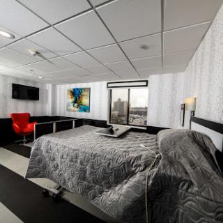 A modern hotel room featuring a comfortable bed, stylish furniture, and a view through the window.