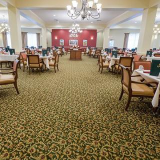 Elegant dining room with neatly arranged tables, chairs, and chandeliers.