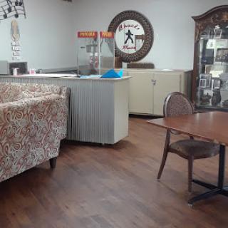 A cozy caf interior featuring a patterned sofa, wooden flooring, and a display case.