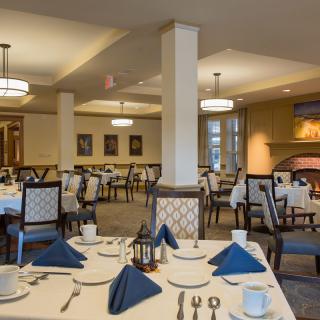 An elegant dining room with neatly set tables and blue napkins.