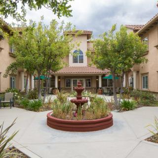 A tranquil courtyard featuring a central fountain surrounded by trees and outdoor seating.