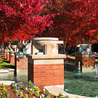 A scenic outdoor fountain surrounded by vibrant red autumn trees.