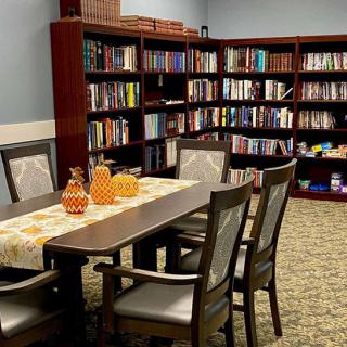 A cozy library corner with bookshelves lining the walls and a table set for reading.