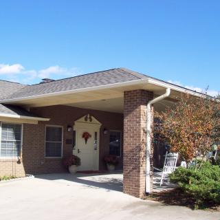 A suburban house with a brick exterior and a driveway under a clear blue sky.